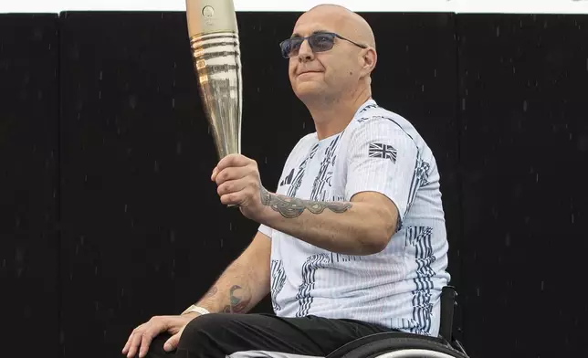 British Paralympian Gregor Ewan holds the Paralympic Torch during the flame lighting ceremony in Stoke Mandeville, widely considered the birthplace of the Paralympic Games, England, Saturday, Aug. 24, 2024. (AP Photo/Thomas Krych)