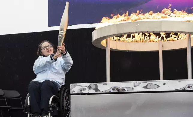 British Paralympian Helene Raynsford holds the Paralympic Torch during the flame lighting ceremony in Stoke Mandeville, widely considered the birthplace of the Paralympic Games, England, Saturday, Aug. 24, 2024. (AP Photo/Thomas Krych)