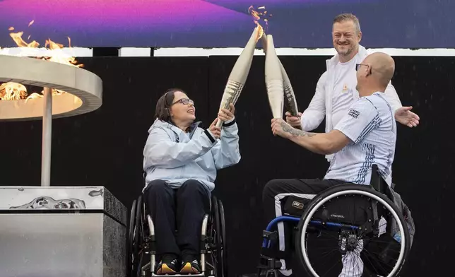 British Paralympians Helene Raynsford and Gregor Ewan light the Paralympic Flame in Stoke Mandeville, widely considered the birthplace of the Paralympic Games, England, Saturday, Aug. 24, 2024. (AP Photo/Thomas Krych)