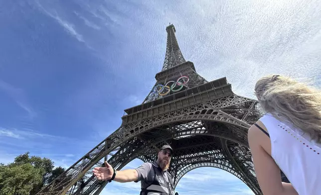 Police evacuate the area around the Eiffel Tower after a man was seen climbing the historic landmark, during the 2024 Summer Olympics, Sunday, Aug. 11, 2024, in Paris France. (AP Photo/Aijaz Rahi)