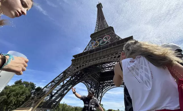 Police evacuate the area around the Eiffel Tower after a man was seen climbing the historic landmark, during the 2024 Summer Olympics, Sunday, Aug. 11, 2024, in Paris France. (AP Photo/Aijaz Rahi)