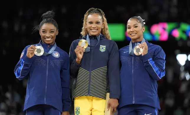 Gold medalist Rebeca Andrade, center, of Brazil, celebrates on the podium between silver medalist Simone Biles, left, and bronze medalist Jordan Chiles, both of the United States, during the medal ceremony for the women's artistic gymnastics individual floor finals at Bercy Arena at the 2024 Summer Olympics, Monday, Aug. 5, 2024, in Paris, France. (AP Photo/Abbie Parr)