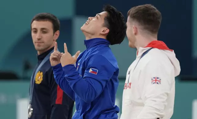 Silver medalist Artur Davtyan, left, of Armenia, stands in the podium with gold medalist Carlos Edriel Yulo, center, of the Philippines, and bronze medalist Harry Hepworth, of Britain, during the medal ceremony for the men's artistic gymnastics individual vault finals at Bercy Arena at the 2024 Summer Olympics, Sunday, Aug. 4, 2024, in Paris, France.(AP Photo/Abbie Parr)