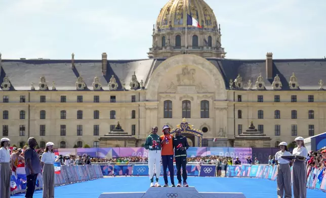 Gold medalist Sifan Hassan, of the Netherlands, center, silver medalist Ethiopia's Tigst Assefa, left, and bronze medalist Kenya's Hellen Obiri, right, pose for photographers during the victory ceremony at the end of the women's marathon competition at the 2024 Summer Olympics, Sunday, Aug. 11, 2024, in Paris, France. (AP Photo/Vadim Ghirda)