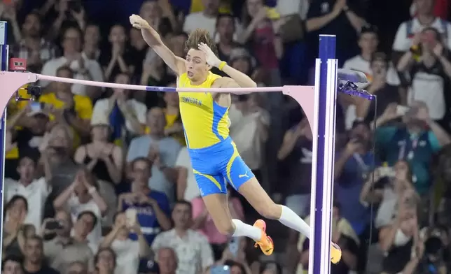 Armand Duplantis, of Sweden, clears the bar at 6.25 to set a new world record during the men's pole vault final at the 2024 Summer Olympics, Monday, Aug. 5, 2024, in Saint-Denis, France. (AP Photo/Martin Meissner)