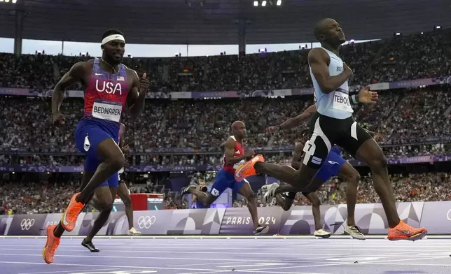 Letsile Tebogo, of Botswana, right, wins the men's 200-meters final at the 2024 Summer Olympics, Thursday, Aug. 8, 2024, in Saint-Denis, France. (AP Photo/David J. Phillip)