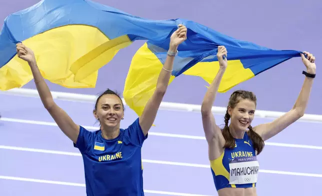 Iryna Gerashchenko, left, and Yaroslava Mahuchikh, both of Ukraine, take a victory lap after Mahuchikh won the gold and Gerashchenko won the bronze medal in the women's high jump at the 2024 Summer Olympics, Sunday, Aug. 4, 2024, in Saint-Denis, France. (AP Photo/David Goldman)