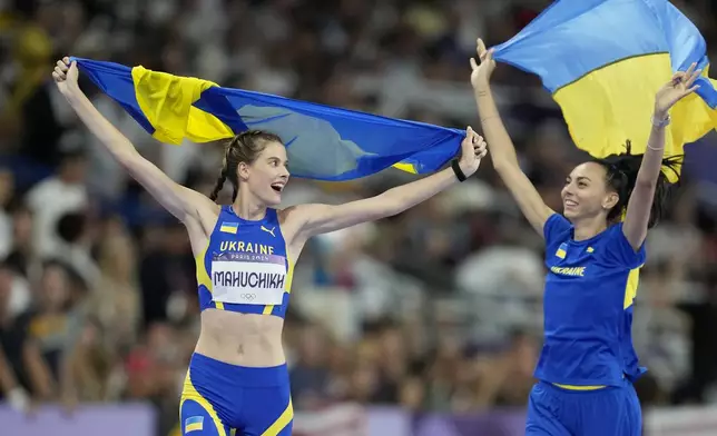 Gold medalist Yaroslava Mahuchikh, and bronze medalist Iryna Gerashchenko, both of Ukraine, celebrate after the the women's high jump final at the 2024 Summer Olympics, Sunday, Aug. 4, 2024, in Saint-Denis, France. (AP Photo/Ashley Landis)