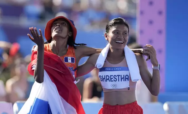 Sifan Hassan, of the Netherlands,left, and Nepal's Shantoshi Shrestha, right, celebrate after crossing the finish line at the end of the women's marathon competition at the 2024 Summer Olympics, Sunday, Aug. 11, 2024, in Paris, France. (AP Photo/Vadim Ghirda)