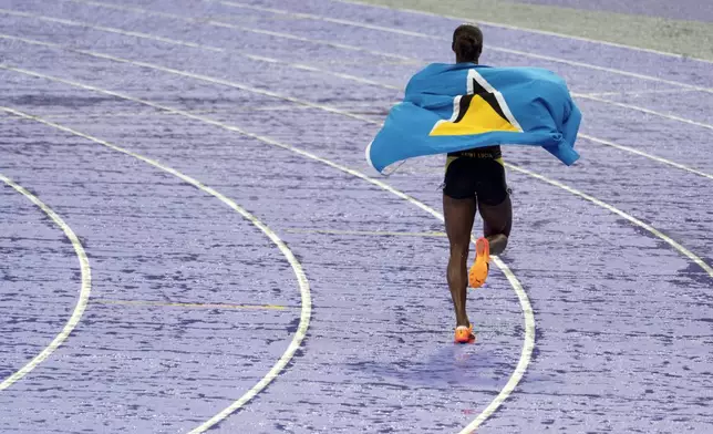 Julien Alfred, of Saint Lucia, takes a victory lap after winning the women's 100-meter final at the 2024 Summer Olympics, Saturday, Aug. 3, 2024, in Saint-Denis, France. (AP Photo/David Goldman)