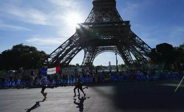 Competitors run past the Eiffel Tower during the men's marathon at the 2024 Summer Olympics, Saturday, Aug. 10, 2024, in Paris, France. (AP Photo/Rebecca Blackwell, Pool)