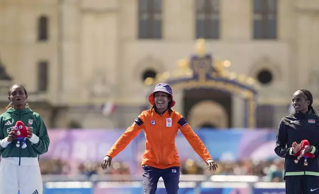 Gold medalist Sifan Hassan, of the Netherlands, center, silver medalist Ethiopia's Tigst Assefa, left, and bronze medalist Kenya's Hellen Obiri, right, pose for photographers during the victory ceremony at the end of the women's marathon competition at the 2024 Summer Olympics, Sunday, Aug. 11, 2024, in Paris, France. (AP Photo/Vadim Ghirda)