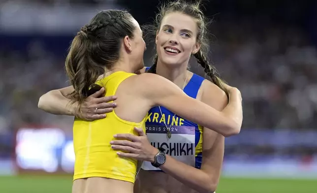 Yaroslava Mahuchikh, right, of Ukraine, is congraulated by Nicola Olyslagers, of Australia, left, after winning the women's high jump final at the 2024 Summer Olympics, Sunday, Aug. 4, 2024, in Saint-Denis, France. (AP Photo/Matthias Schrader)