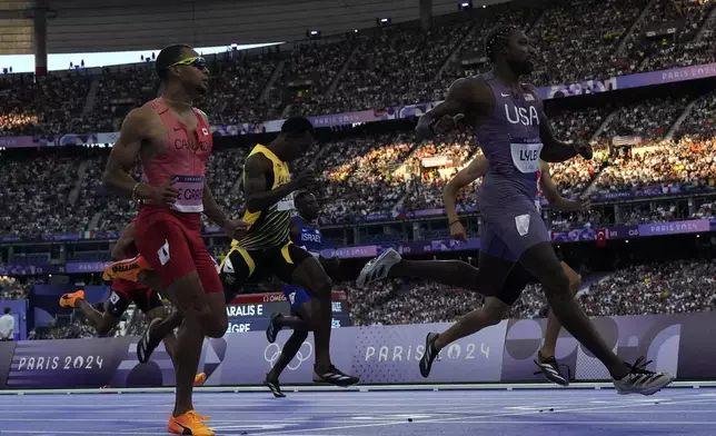 Noah Lyles, of the United States, crosses the finish line ahead of Andre de Grasse, left, of Canada, to win his men's 200-meters' heat at the 2024 Summer Olympics, Monday, Aug. 5, 2024, in Saint-Denis, France. (AP Photo/David J. Phillip)