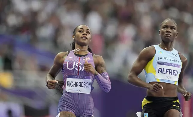 Sha'carri Richardson, of the United States, and Julien Alfred, of Saint Lucia, check the results after finishing a women's 100 meters semifinal at the 2024 Summer Olympics, Saturday, Aug. 3, 2024, in Saint-Denis, France. (AP Photo/Ashley Landis)