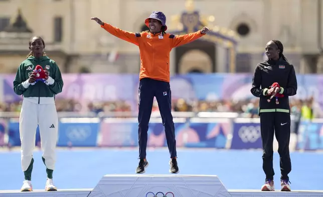 Gold medalist Sifan Hassan, of the Netherlands, center, silver medalist Ethiopia's Tigst Assefa, left, and bronze medalist Kenya's Hellen Obiri, right, pose for photographers during the victory ceremony at the end of the women's marathon competition at the 2024 Summer Olympics, Sunday, Aug. 11, 2024, in Paris, France. (AP Photo/Vadim Ghirda)