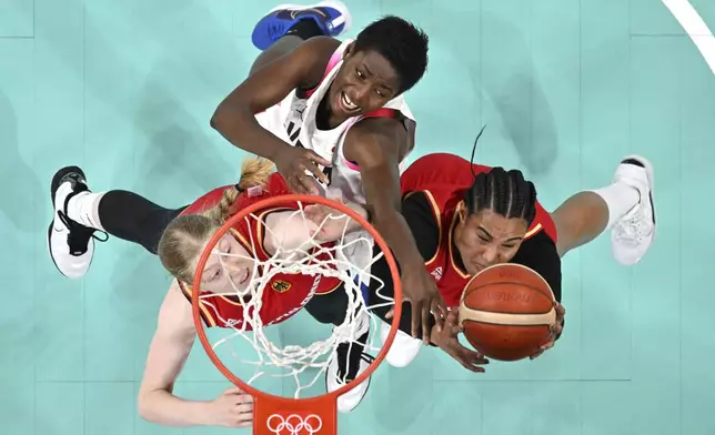 Germany's Frieda Buhner, left, and Germany's Satou Sabally, right, reach for a rebound along with Japan's Evelyn Mawuli in a women's basketball game at the 2024 Summer Olympics, Thursday, Aug. 1, 2024, in Villeneuve-d'Ascq, France. (Sameer Al-Doumy/Pool Photo via AP)