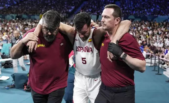 Spain's Rudy Fernandez, center, is held off the court after being injured in a men's basketball game against Greece at the 2024 Summer Olympics, Tuesday, July 30, 2024, in Villeneuve-d'Ascq, France. (AP Photo/Michael Conroy)