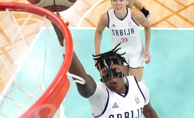 Serbia's Yvonne Anderson, below, shoots as Serbia's Tina Kajisnik, center, and Spain's Maite Cazorla watch during a women's basketball game at the 2024 Summer Olympics, Saturday, Aug. 3, 2024, in Villeneuve-d'Ascq, France. (AP Photo/Michael Conroy, Pool)