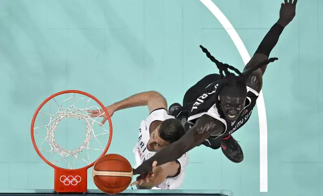 Serbia's Aleksa Avramovic, left, shoots as South Sudan's Wenyen Gabriel defends at the 2024 Summer Olympics, Saturday, Aug. 3, 2024, in Villeneuve-d'Ascq, France. (Sameer Al-Doumy/Pool Photo via AP)