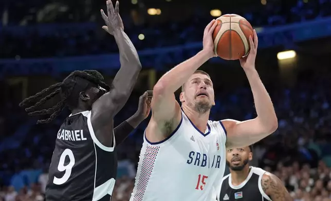 Serbia's Nikola Jokic, center, shoots as South Sudan's Wenyen Gabriel, left, defends during a men's basketball game at the 2024 Summer Olympics, Saturday, Aug. 3, 2024, in Villeneuve-d'Ascq, France. (AP Photo/Michael Conroy)