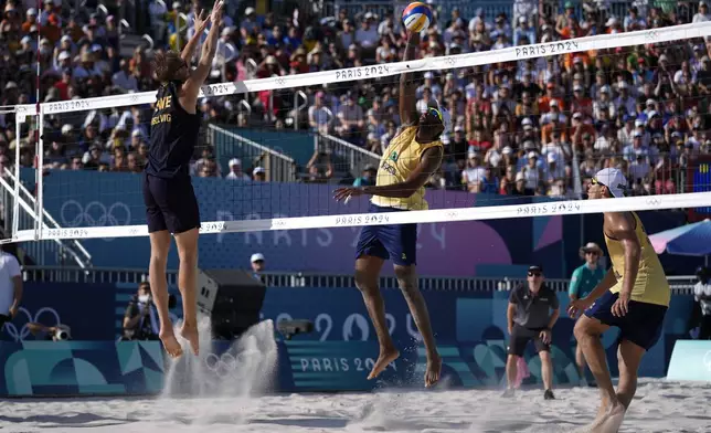 Brazil's Evandro Goncalves Oliveira Junior goes up for a shot against Sweden's Jonatan Hellvig in a quarterfinal beach volleyball match at the 2024 Summer Olympics, Tuesday, Aug. 6, 2024, in Paris, France. (AP Photo/Robert F. Bukaty)