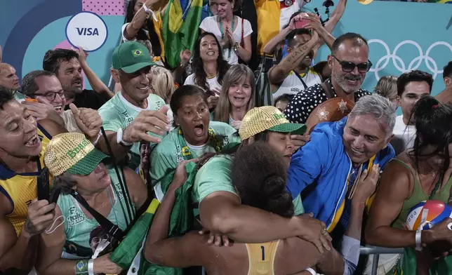Brazil's Ana Patricia Silva Ramos celebrates with fans after Brazil won their women's beach volleyball gold medal match against Canada, at the 2024 Summer Olympics, Friday, Aug. 9, 2024, in Paris, France. (AP Photo/Louise Delmotte)