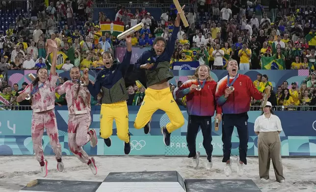 Gold medalists, Brazil's Eduarda "Duda" Santos Lisboa, center left, and Ana Patricia Silva Ramos, center right, jump on the podium as they celebrate with, from left, silver medalists, Canada's Melissa Humana-Paredes and Brandie Wilkerson, and bronze medalists, Switzerland's Nina Brunner and Tanja Hueberli, on the medals podium for women's beach volleyball at the 2024 Summer Olympics, Saturday, Aug. 10, 2024, in Paris, France. (AP Photo/Robert F. Bukaty)
