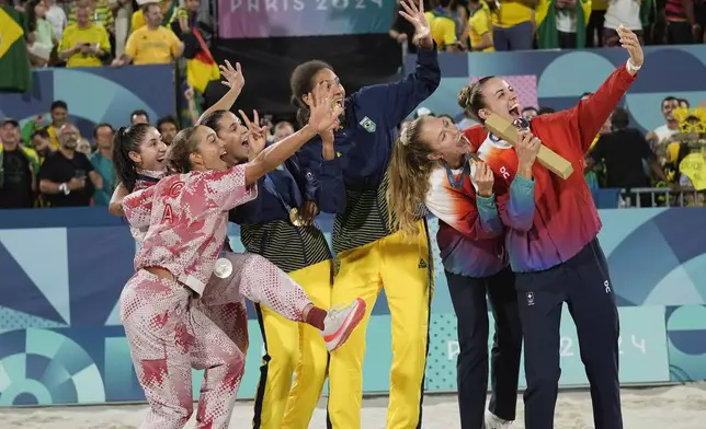 Gold medalists, Brazil's Eduarda "Duda" Santos Lisboa, center left, and Ana Patricia Silva Ramos, center right, pose for a selfie with, from left, silver medalists, Canada's Melissa Humana-Paredes and Brandie Wilkerson, and bronze medalists, Switzerland's Nina Brunner and Tanja Hueberli, on the medals podium for women's beach volleyball at the 2024 Summer Olympics, Saturday, Aug. 10, 2024, in Paris, France. (AP Photo/Robert F. Bukaty)