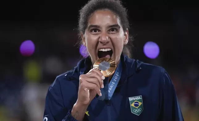 Brazil's Ana Patricia Silva Ramos poses with her gold medal in women's beach volleyball, at the 2024 Summer Olympics, Saturday, Aug. 10, 2024, in Paris, France. (AP Photo/Louise Delmotte)