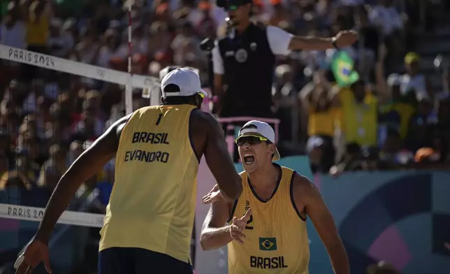 Brazil's Evandro Goncalves Oliveira Junior, left, and Arthur Diego Mariano Lanci react during the men's quarterfinal beach volleyball match between Brazil and Sweden at Eiffel Tower Stadium at the 2024 Summer Olympics, Tuesday, Aug. 6, 2024, in Paris, France. (AP Photo/Louise Delmotte)