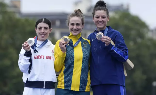 Grace Brown, of Australia, centre, shows the gold medal of the women's cycling time trial event, flanked by silver medallist Anna Henderson, of Britain, left, and bronze medallist Chloe Dygert, of United States, at the 2024 Summer Olympics, Saturday, July 27, 2024, in Paris, France. (AP Photo/Ricardo Mazalan)