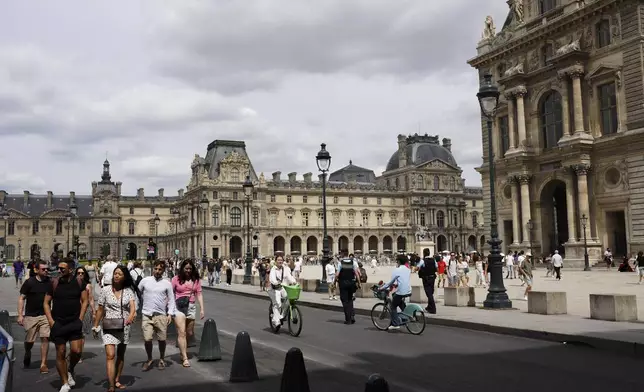 Tourists stroll around during the men's road cycling event, at the 2024 Summer Olympics, Saturday, Aug. 3, 2024, in Paris, France. (AP Photo/Thibault Camus)