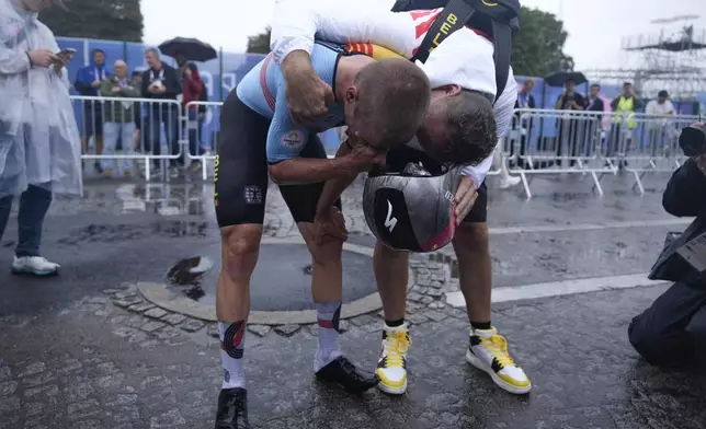 Remco Evenepoel, of Belgium, left, reacts after winning the men's cycling time trial event, at the 2024 Summer Olympics, Saturday, July 27, 2024, in Paris, France. (AP Photo/Ricardo Mazalan)