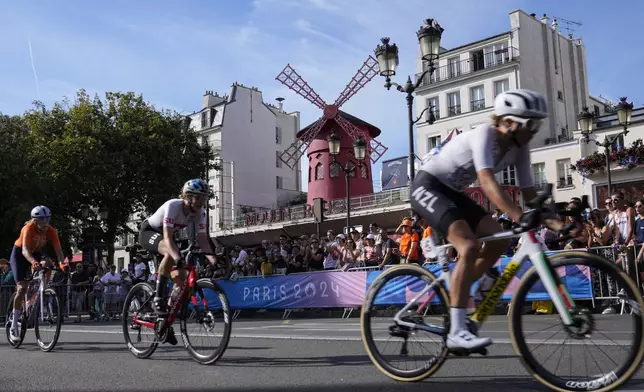 Cyclists ride past the Moulin Rouge cabaret venue, during the women's road cycling event, at the 2024 Summer Olympics, Sunday, Aug. 4, 2024, in Paris, France. (AP Photo/Dar Yasin)