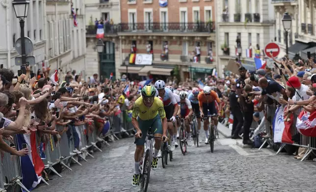 Riders pedal past a cheering crowd, during the men's road cycling event, at the 2024 Summer Olympics, Saturday, Aug. 3, 2024, in Paris, France. (Tim de Waele/Pool Photo via AP)