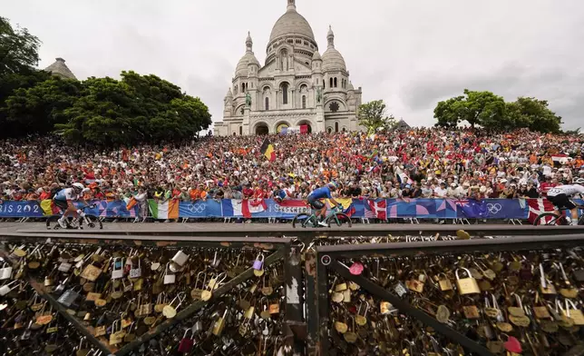 Luca Mozzato, of Italy, centre, rides past the Sacre Coeur basilica, during the men's road cycling event, at the 2024 Summer Olympics, Saturday, Aug. 3, 2024, in Paris, France. (AP Photo/Vadim Ghirda)