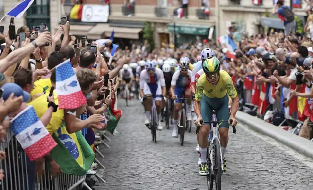 Riders are cheered by spectators during the men's road cycling event, at the 2024 Summer Olympics, Saturday, Aug. 3, 2024, in Paris, France. (Tim de Waele/Pool Photo via AP)