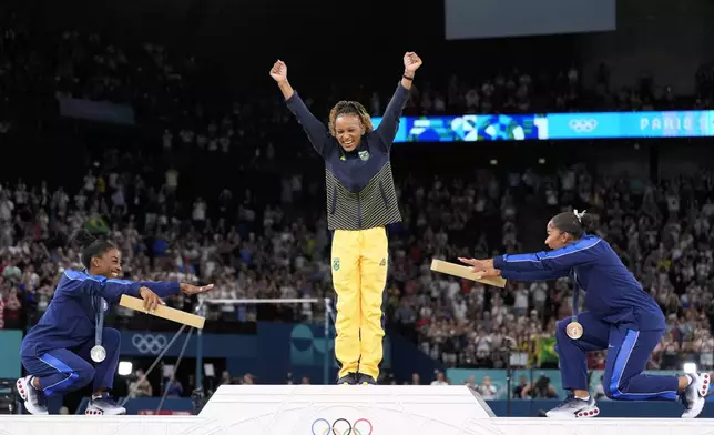 Silver medalist Simone Biles, of the United States, left, and bronze medalist Jordan Chiles, of the United States, right, bow to gold medalist Rebeca Andrade, of Brazil, during the medal ceremony for the women's artistic gymnastics individual floor finals at Bercy Arena at the 2024 Summer Olympics, Monday, Aug. 5, 2024, in Paris, France. (AP Photo/Abbie Parr)