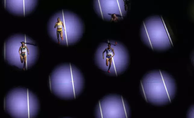 Miranda Charlene Coetzee, of South Africa, Modesta Juste Morauskaite, of Lithuania, and Gabby Scott, of Puerto Rico, from left, seen through a metal barrier, run in a women's 400 meters repechage heat at the 2024 Summer Olympics, Tuesday, Aug. 6, 2024, in Saint-Denis, France. (AP Photo/Ashley Landis)