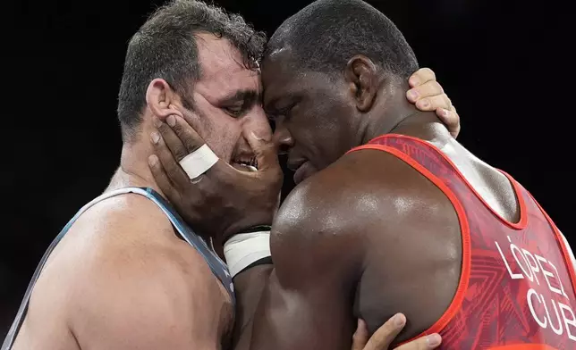 Cuba's Mijain Lopez and Azerbaijan's Sabah Shariati, left, compete during their men's Greco-Roman 130kg wrestling semifinal match, at Champ-de-Mars Arena, during the 2024 Summer Olympics, Monday, Aug. 5, 2024, in Paris, France. (AP Photo/Eugene Hoshiko)