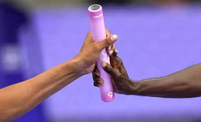 Athletes from Trinidad and Tabago exchange a baton during the men's 4x400-meter relay heat at the 2024 Summer Olympics, Friday, Aug. 9, 2024, in Saint-Denis, France. (AP Photo/Matthias Schrader)