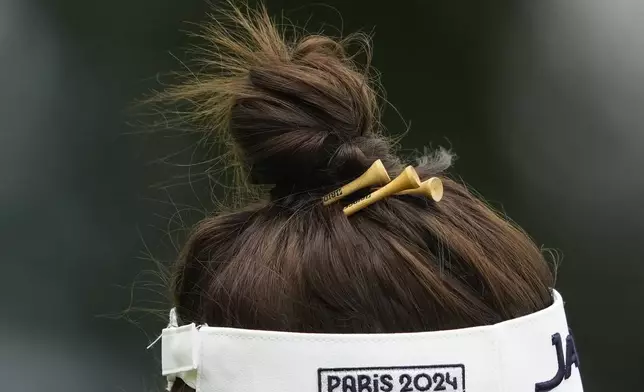 Miyu Yamashita, of Japan, has tees in her hair as she walks along the 13th hole during the third round of the women's golf event at the 2024 Summer Olympics, Friday, Aug. 9, 2024, at Le Golf National, in Saint-Quentin-en-Yvelines, France. (AP Photo/Matt York)