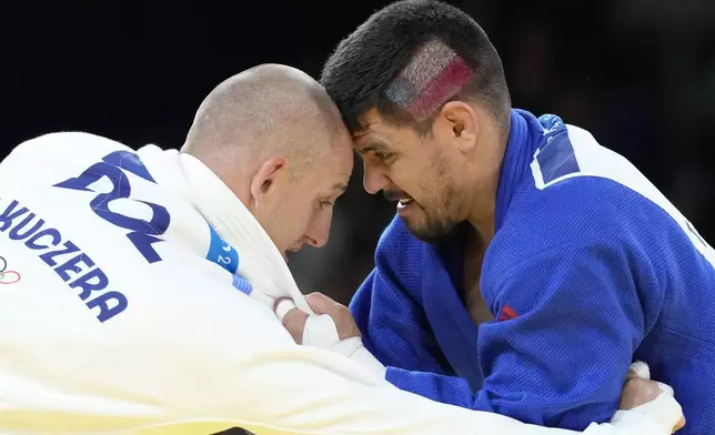 Poland's Piotr Kuczera and Chile's Thomas Briceno compete during their men's -100 kg elimination round match in the team judo competition, at Champ-de-Mars Arena, during the 2024 Summer Olympics, Thursday, Aug. 1, 2024, in Paris, France. (AP Photo/Eugene Hoshiko)