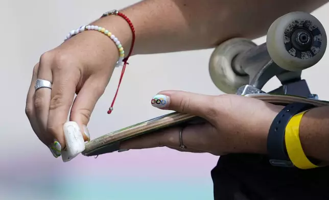 Haylie Powell, of Australia, wearing the Olympic rings on her thumbnail, waxes her board during the women's skateboard street preliminaries at the 2024 Summer Olympics, Sunday, July 28, 2024, in Paris, France. (AP Photo/Frank Franklin II)