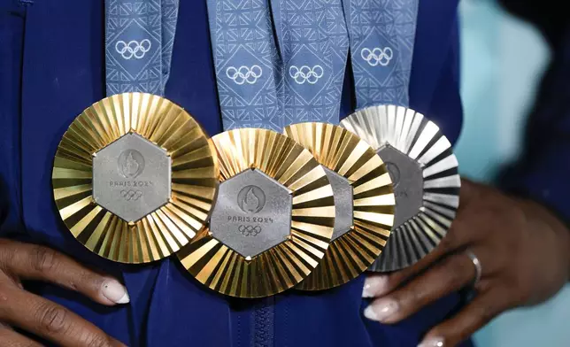 Simone Biles, of the United States, holds up her medals after the women's artistic gymnastics individual apparatus finals Bercy Arena at the 2024 Summer Olympics, Monday, Aug. 5, 2024, in Paris, France. (AP Photo/Charlie Riedel)