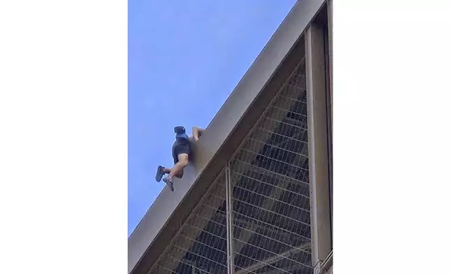 In this photo provided by Nickey Worlock, a man climbs the Eiffel Tower, during the 2024 Summer Olympics, Sunday, Aug. 11, 2024, in Paris France. (Nickey Worlock via AP)