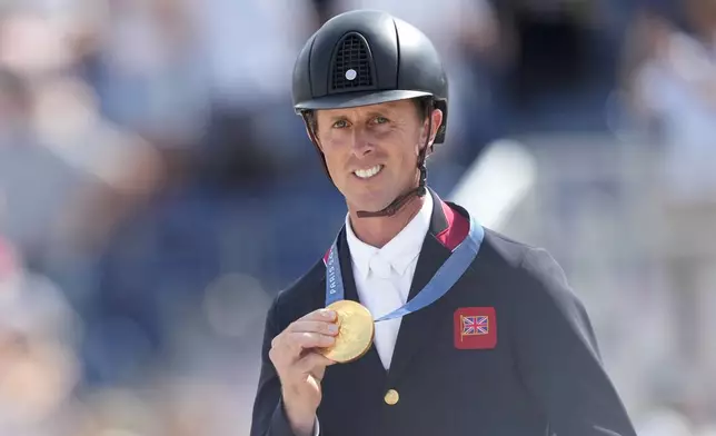 Britain's Ben Maher shows his gold medal after the Equestrian Jumping Team final at the 2024 Summer Olympics, Friday, Aug. 2, 2024, in Versailles, France. (AP Photo/Mosa'ab Elshamy)