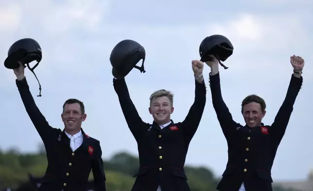 Britain's Scott Brash, right, Harry Charles, center, and Ben Maher celebrate after winning the gold medal the Equestrian Jumping Team final at the 2024 Summer Olympics, Friday, Aug. 2, 2024, in Versailles, France. (AP Photo/=03387382=)