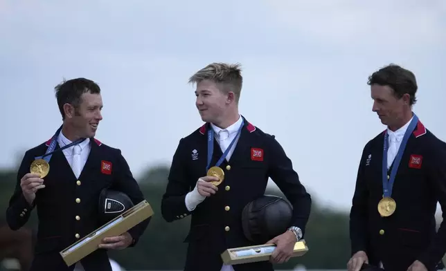 Britain's Scott Brash, left, Harry Charles, center, and Ben Maher show their gold medal after the Equestrian Jumping Team final at the 2024 Summer Olympics, Friday, Aug. 2, 2024, in Versailles, France. (AP Photo/Mosa'ab Elshamy)